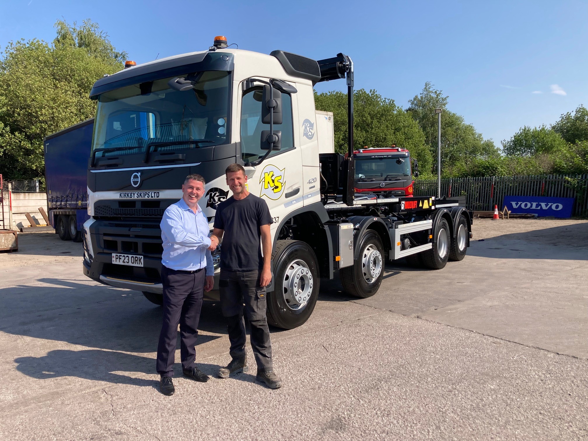 New Volvo FMX13 Truck handed over to Kirkby Skips, Liverpool. Image shows two men looking towards the camera and shaking hands in front of the Volvo truck which has a white cab with the Kirkby skips logo on it.